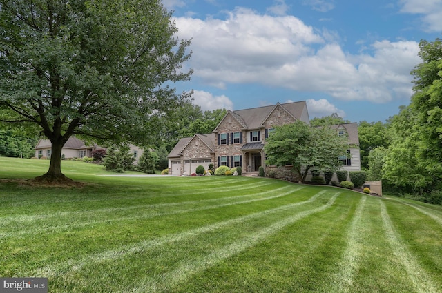 view of front facade featuring stone siding, a standing seam roof, a front lawn, and a garage