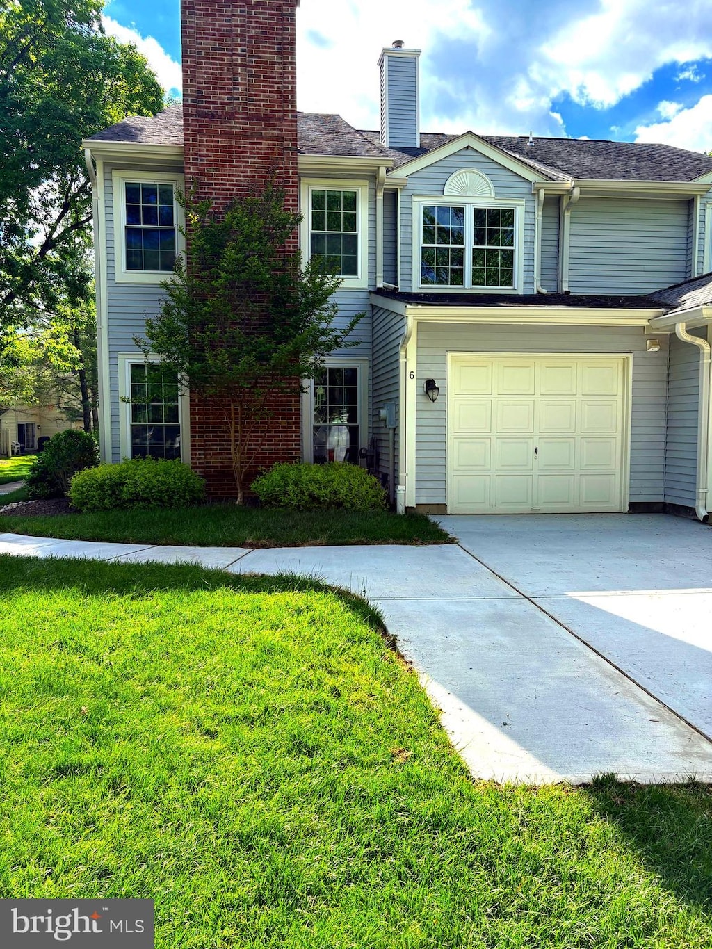 view of front of property featuring driveway, a chimney, and a front yard