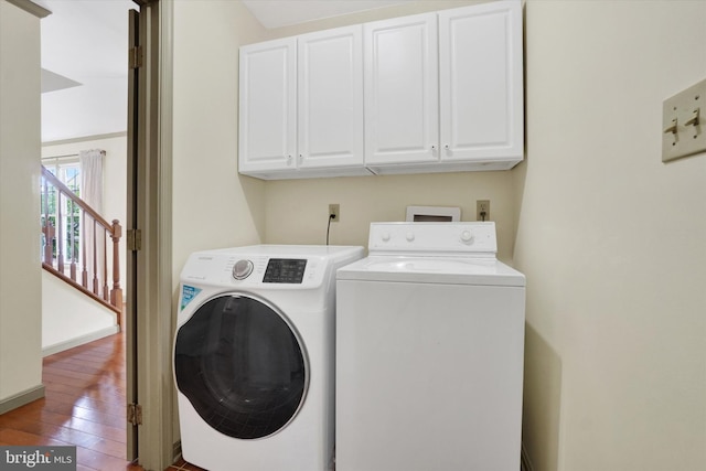 laundry room with washer and clothes dryer, cabinet space, and wood finished floors