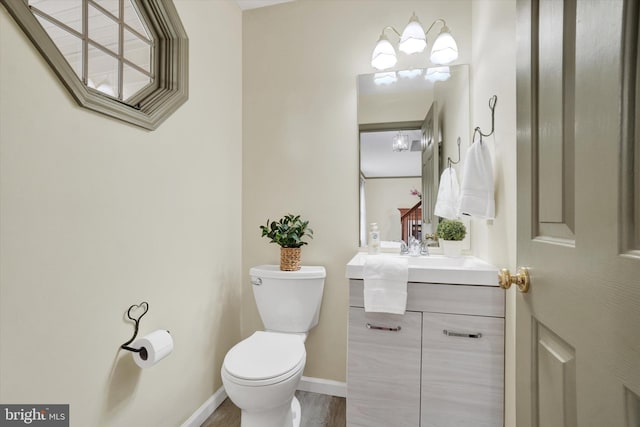 bathroom with toilet, vanity, and baseboards