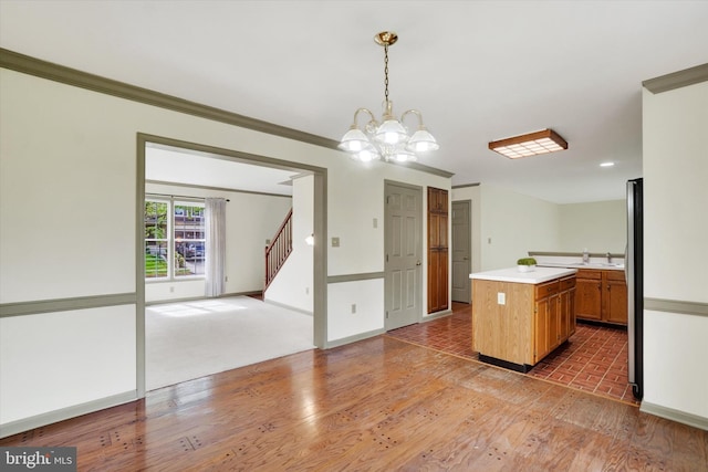 kitchen featuring light countertops, a chandelier, light wood-type flooring, a center island, and hanging light fixtures