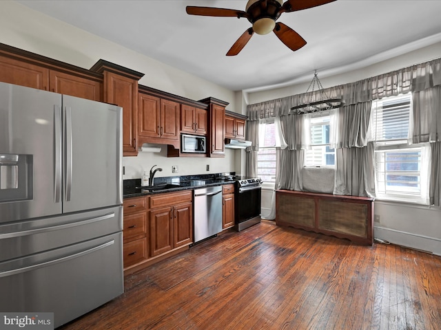 kitchen featuring a sink, stainless steel appliances, under cabinet range hood, a ceiling fan, and dark wood-style floors