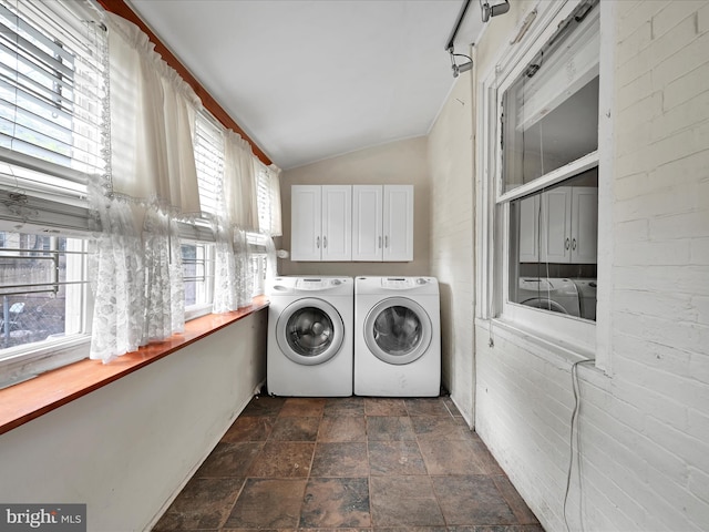clothes washing area featuring stone finish floor, washer and dryer, and cabinet space