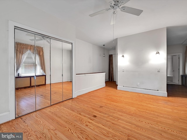 unfurnished bedroom featuring ceiling fan, baseboards, a closet, and wood finished floors