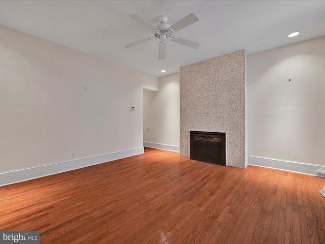unfurnished living room featuring a ceiling fan, recessed lighting, baseboards, wood finished floors, and a large fireplace
