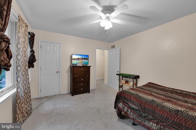 bedroom with a ceiling fan, light carpet, and baseboards
