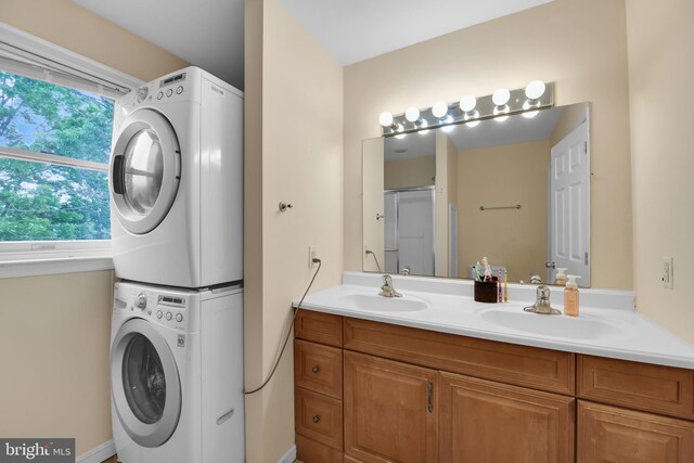 full bath featuring stacked washing machine and dryer and double vanity
