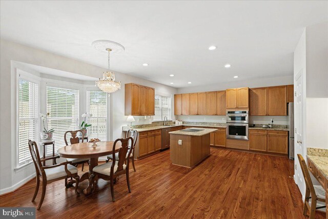 kitchen featuring stainless steel appliances, a kitchen island, dark wood-style flooring, a chandelier, and hanging light fixtures