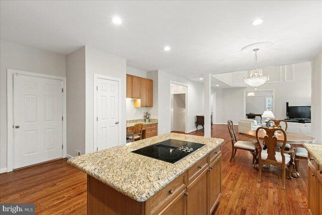 kitchen with black electric cooktop, dark wood-type flooring, a center island, recessed lighting, and light stone countertops