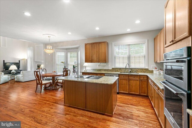 kitchen with appliances with stainless steel finishes, a sink, a center island, light wood-style floors, and recessed lighting