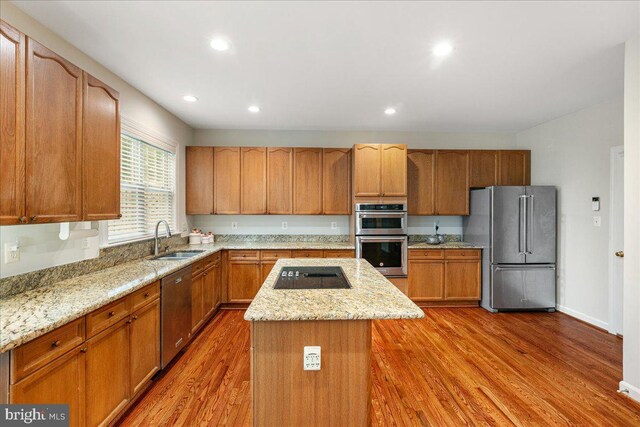 kitchen with stainless steel appliances, a sink, a center island, wood finished floors, and recessed lighting