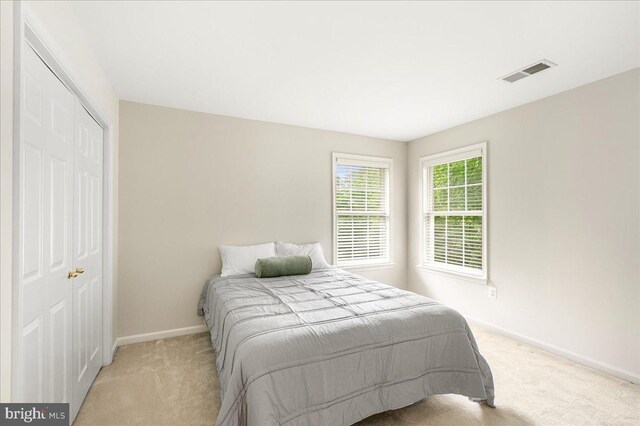 bedroom with light colored carpet, baseboards, and a closet