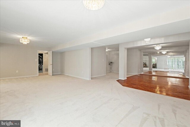 unfurnished living room with carpet, a chandelier, and baseboards
