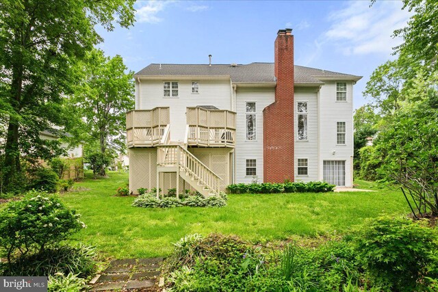 rear view of property with stairs, a chimney, a lawn, and a wooden deck