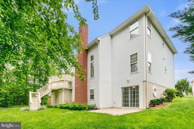 rear view of house with a chimney, a yard, stairs, and a patio