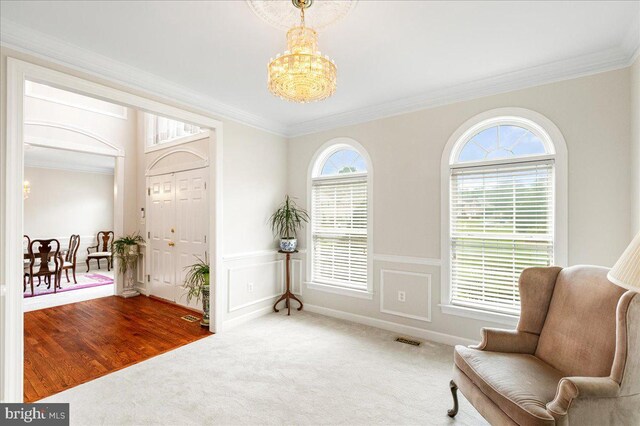 entryway with a chandelier, crown molding, and carpet