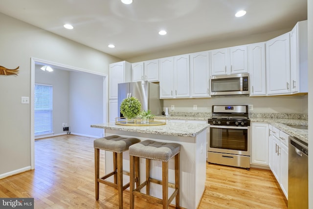 45559 Grand Central Sq, Sterling, VA 20166 - kitchen featuring stainless steel appliances, a kitchen bar, white cabinetry, light wood-style flooring, and a kitchen island