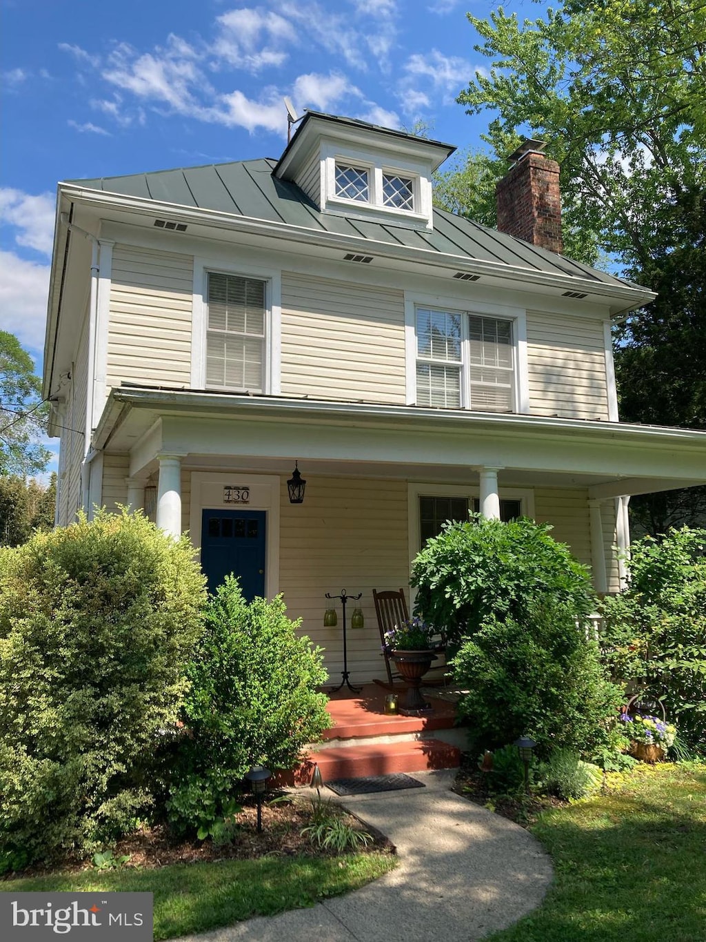 traditional style home with a standing seam roof, a porch, a chimney, and metal roof