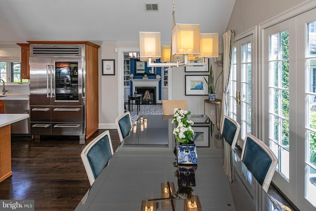 dining area featuring lofted ceiling, dark wood-type flooring, visible vents, a fireplace, and baseboards