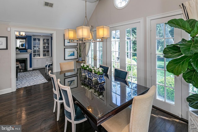 dining area with a fireplace with flush hearth, plenty of natural light, dark wood-type flooring, and visible vents