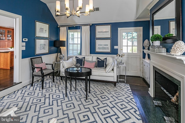living room with a premium fireplace, an inviting chandelier, visible vents, and wainscoting