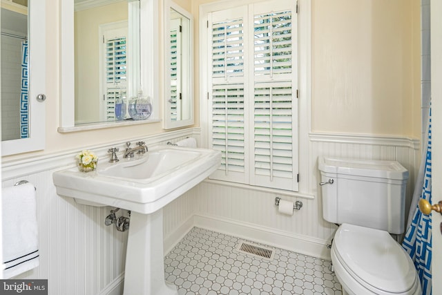 bathroom with toilet, wainscoting, and visible vents