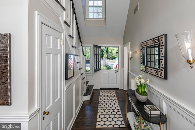 entryway with a healthy amount of sunlight, a decorative wall, high vaulted ceiling, and visible vents