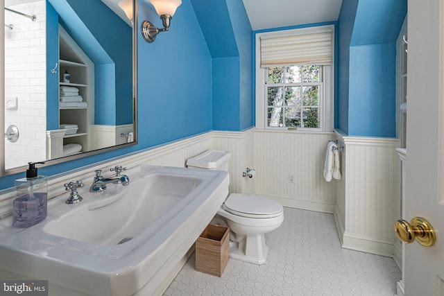 full bathroom with a sink, walk in shower, toilet, a wainscoted wall, and tile patterned floors