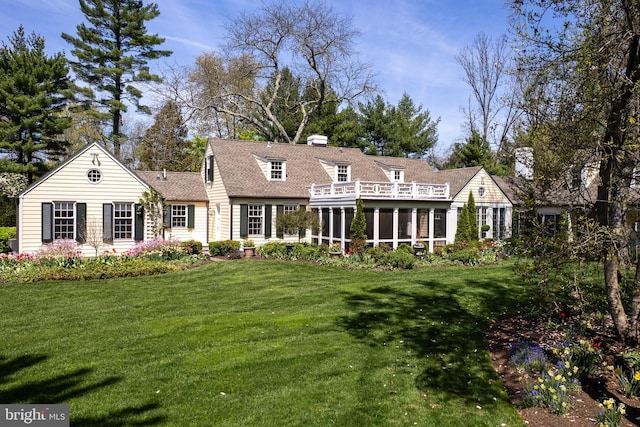 view of front of house featuring a front lawn, a shingled roof, a sunroom, and a chimney