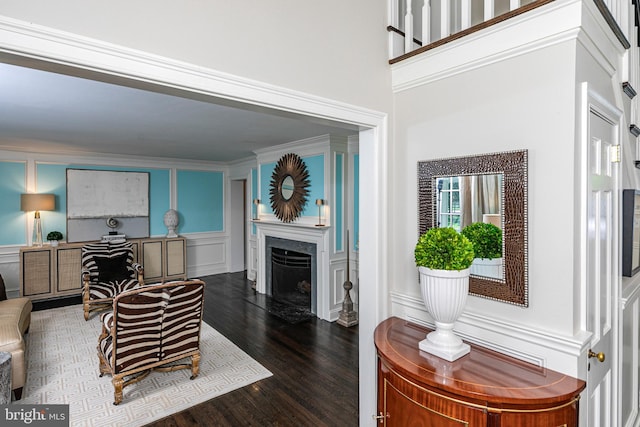 living room featuring dark wood finished floors, a decorative wall, and a fireplace