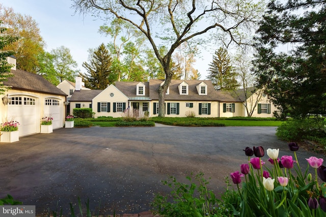 cape cod home featuring a garage and driveway