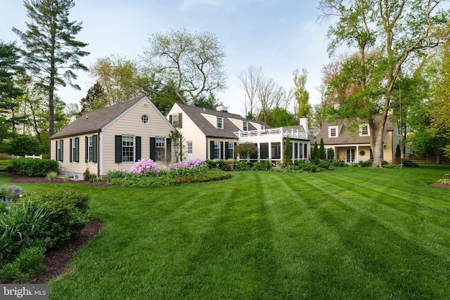 rear view of house featuring a sunroom, a chimney, and a lawn