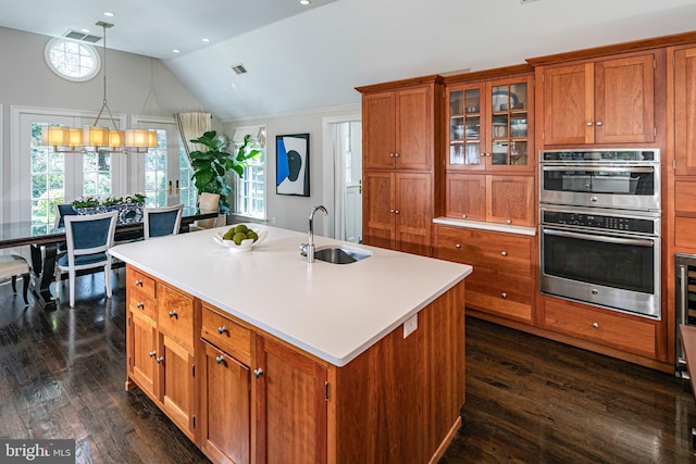 kitchen featuring dark wood finished floors, vaulted ceiling, brown cabinetry, and a sink