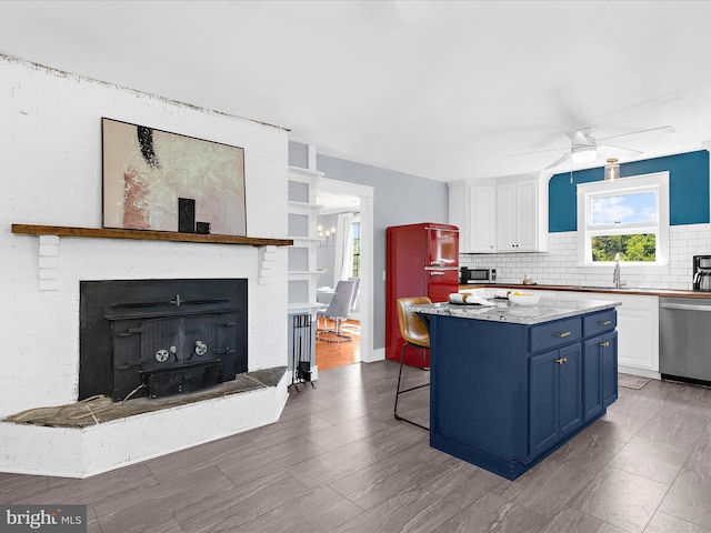 1990 Kate Dr, Port Republic, MD 20676 - kitchen featuring appliances with stainless steel finishes, white cabinetry, blue cabinetry, a center island, and ceiling fan