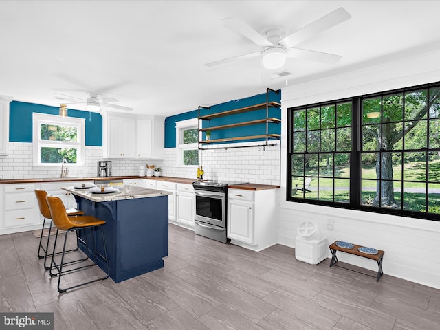 1990 Kate Dr, Port Republic, MD 20676 - kitchen with stainless steel electric range, ceiling fan, a sink, white cabinetry, and tasteful backsplash