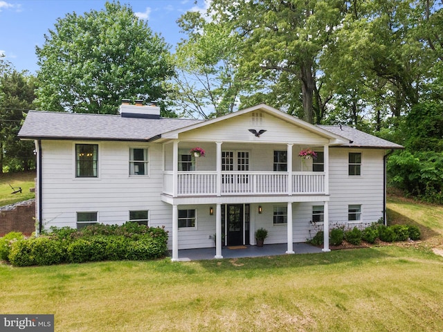 1990 Kate Dr, Port Republic, MD 20676 - rear view of property featuring a balcony, a yard, a patio, a shingled roof, and a chimney