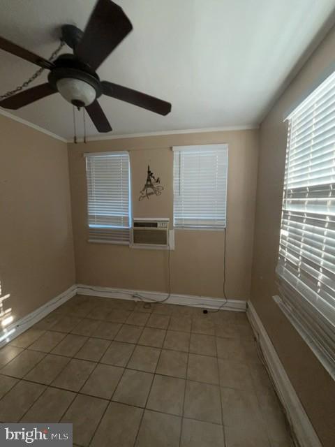 spare room featuring ornamental molding, cooling unit, a ceiling fan, light tile patterned floors, and baseboards