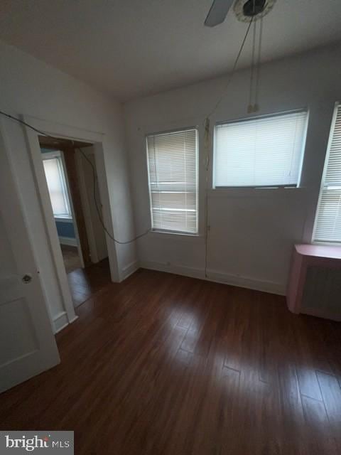unfurnished room featuring baseboards, wood finished floors, and a ceiling fan