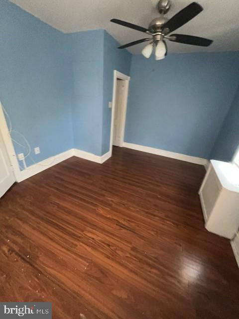 unfurnished room featuring a ceiling fan, baseboards, and wood finished floors