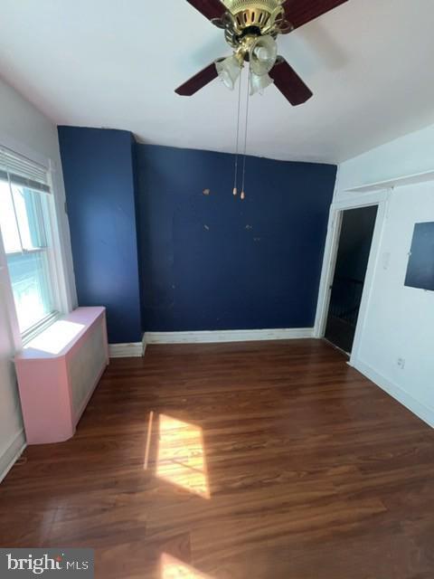 spare room featuring a ceiling fan, wood finished floors, and baseboards