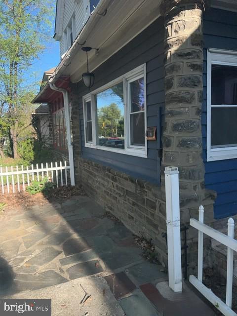 view of side of home with stone siding and fence