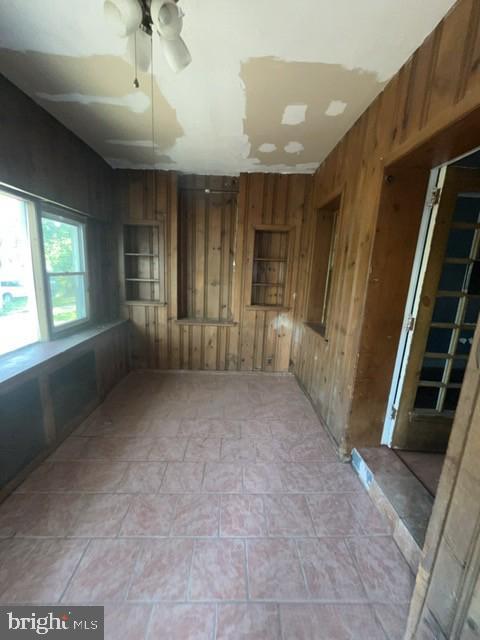 unfurnished room featuring ceiling fan and wood walls