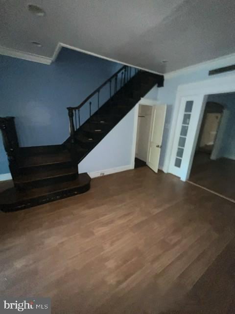 stairway with wood finished floors, baseboards, and ornamental molding