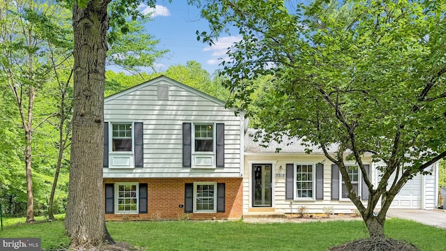 tri-level home featuring a front yard, brick siding, a garage, and driveway
