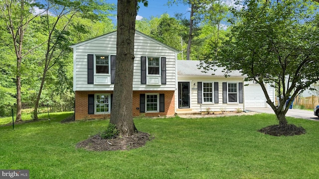 split level home with a garage, brick siding, driveway, and a front yard