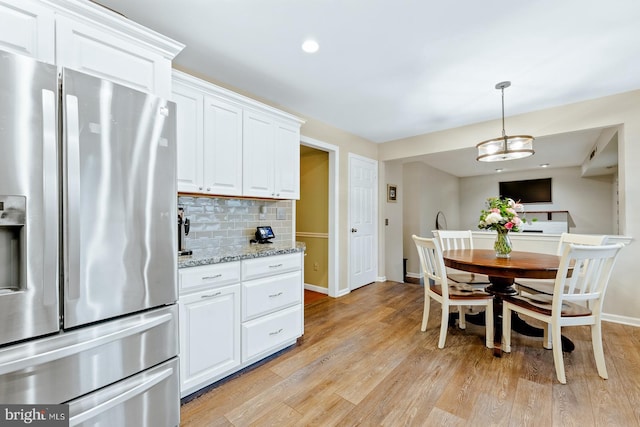 kitchen featuring stainless steel refrigerator with ice dispenser, baseboards, tasteful backsplash, light wood-style flooring, and white cabinetry