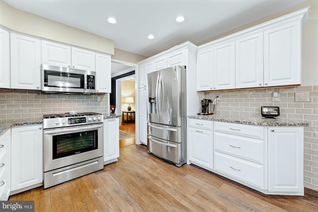 kitchen featuring stainless steel appliances, light wood finished floors, tasteful backsplash, white cabinetry, and recessed lighting