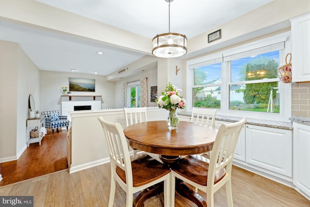 dining room with a brick fireplace, light wood-type flooring, recessed lighting, and baseboards