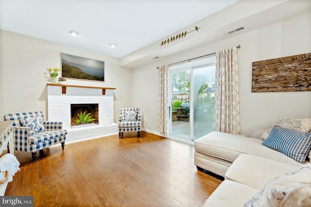 living area with wood finished floors, a brick fireplace, and baseboards