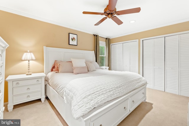 bedroom with light carpet, multiple closets, crown molding, and a ceiling fan